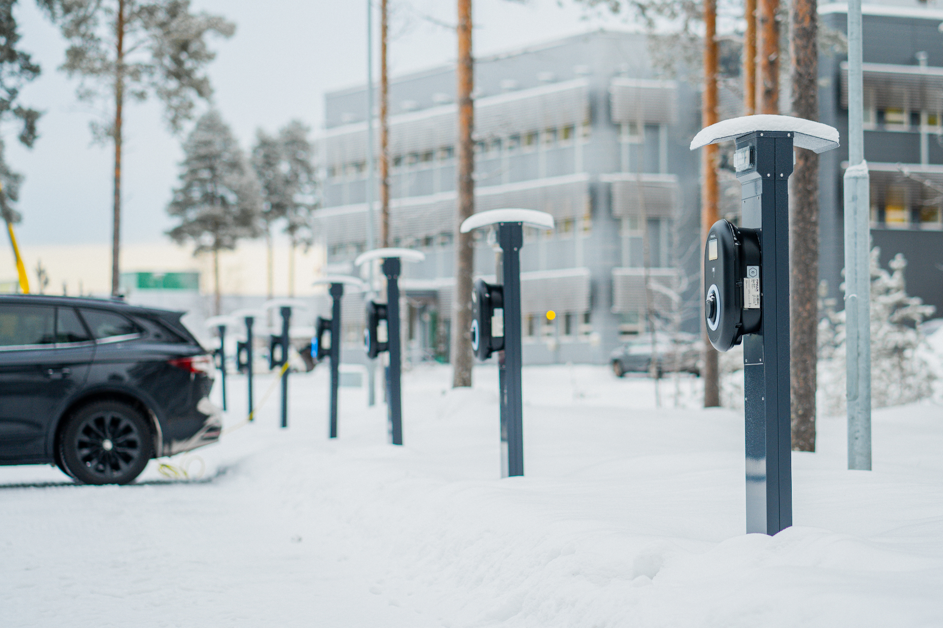 Sähköautojen latausasemia talvisella pysäköintialueella